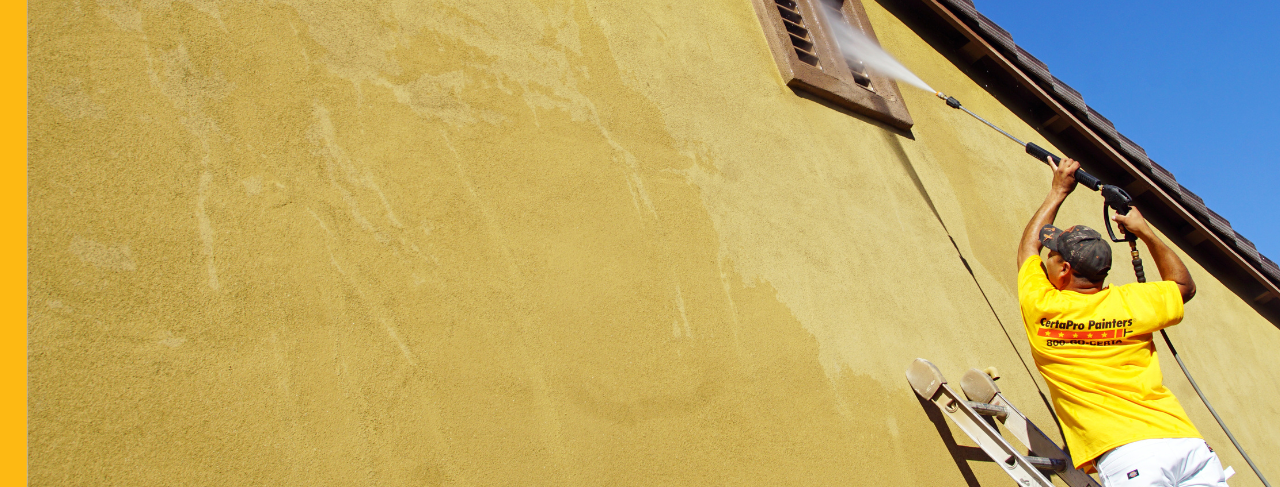 stucco home being power washed by certapro team member